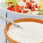 a bowl of homemade Chart House blue cheese dressing in front of a wedge salad