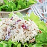 chicken salad with grapes, apples, and pecans on top of lettuce on a plate