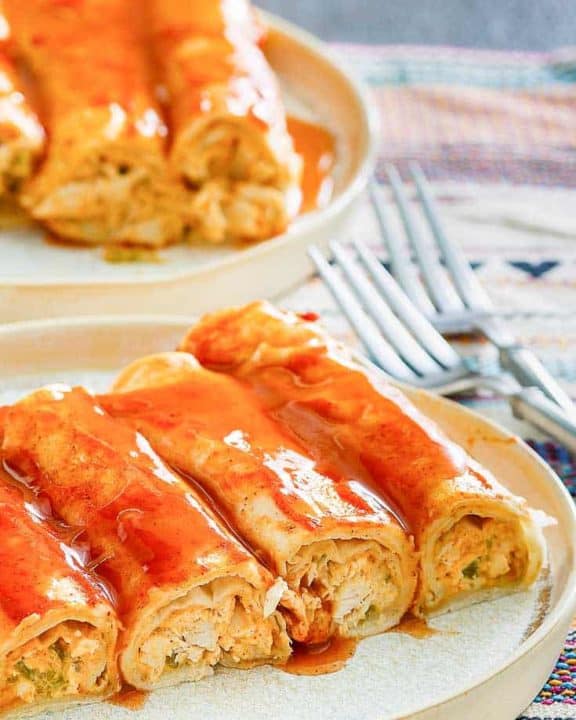 four cream cheese chicken enchiladas and sauce on a plate