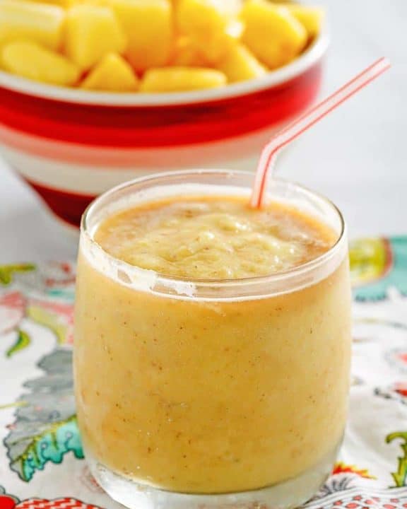 Dole whip with rum float in a glass in front of a bowl of pineapple