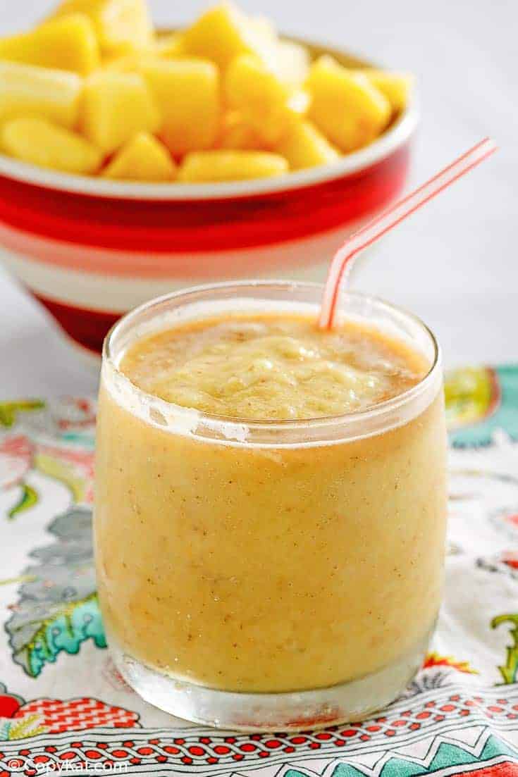 Dole whip with rum float in a glass in front of a bowl of pineapple