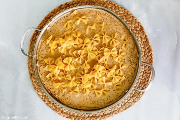 uncooked bowtie pasta and Stroganoff sauce in a skillet