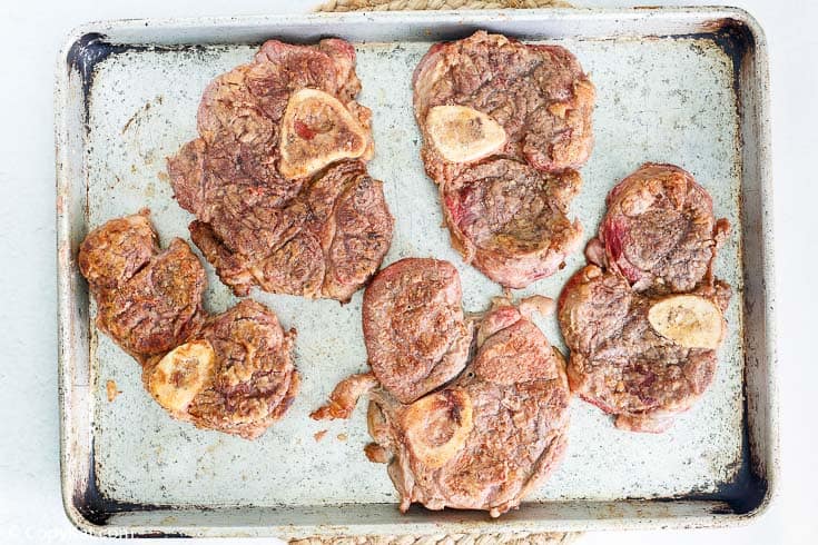 browned beef shanks on a baking sheet