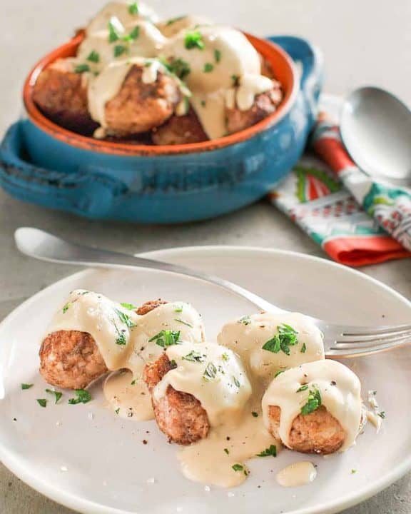 homemade Swedish meatballs and gravy on a plate and in a bowl