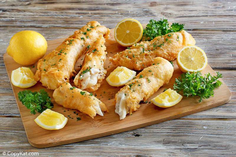 batter fried fish and lemon wedges on a wood platter