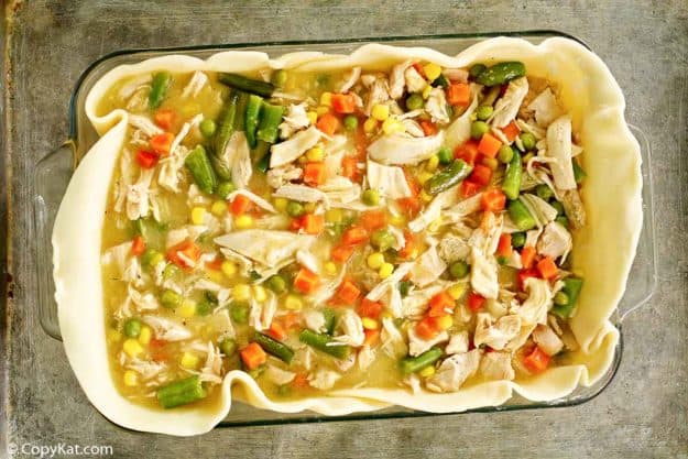 chicken pot pie filling and pie crust in a baking dish