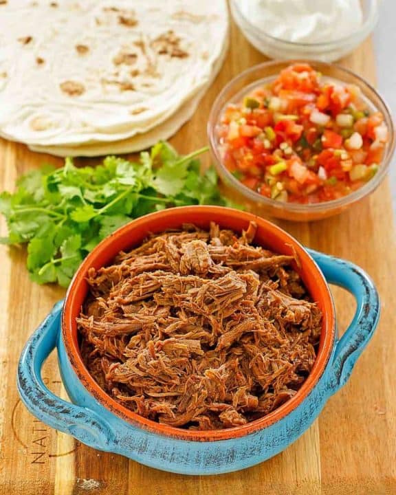 beef barbacoa, cilantro, salsa, tortillas, and sour cream