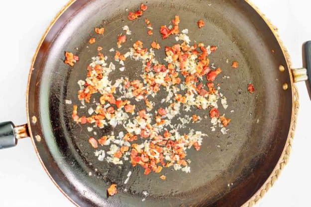 cooked bacon bits and onions in a skillet