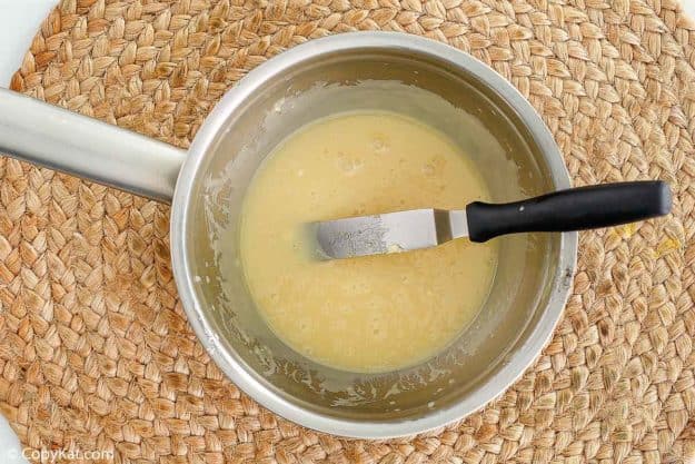 melted white chocolate and a spreader knife in a pan