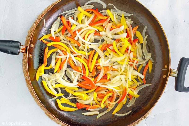 sliced bell peppers and onions in a skillet