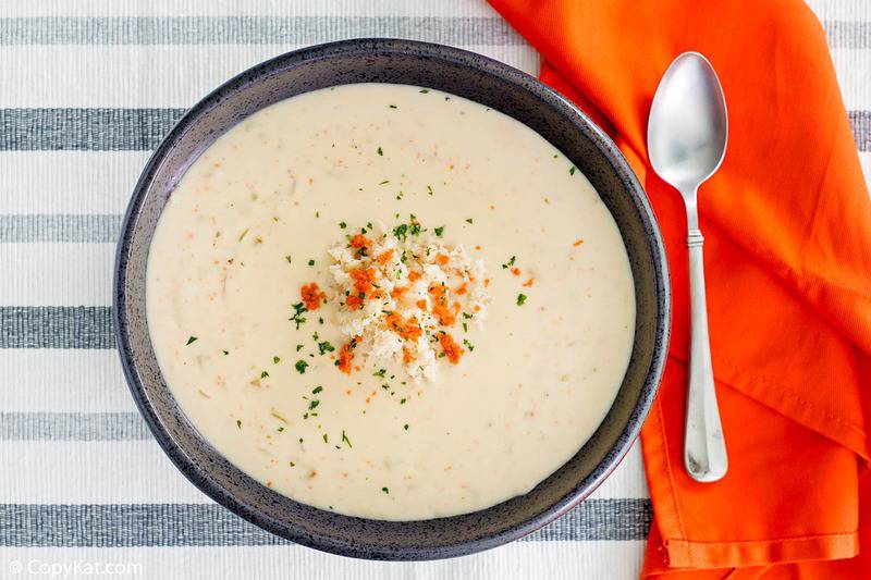 she crab soup in a black bowl, spoon, and orange napkin