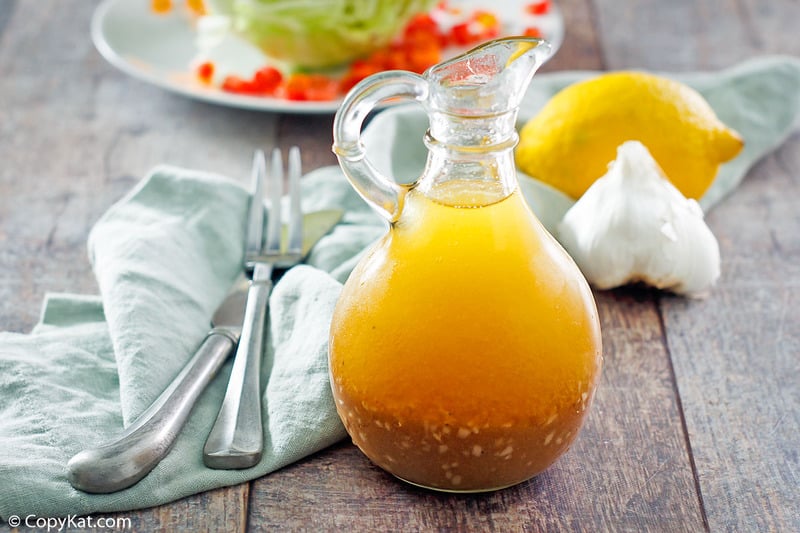 homemade Brown Derby French dressing, a head of garlic, lemon, and cutlery on a table