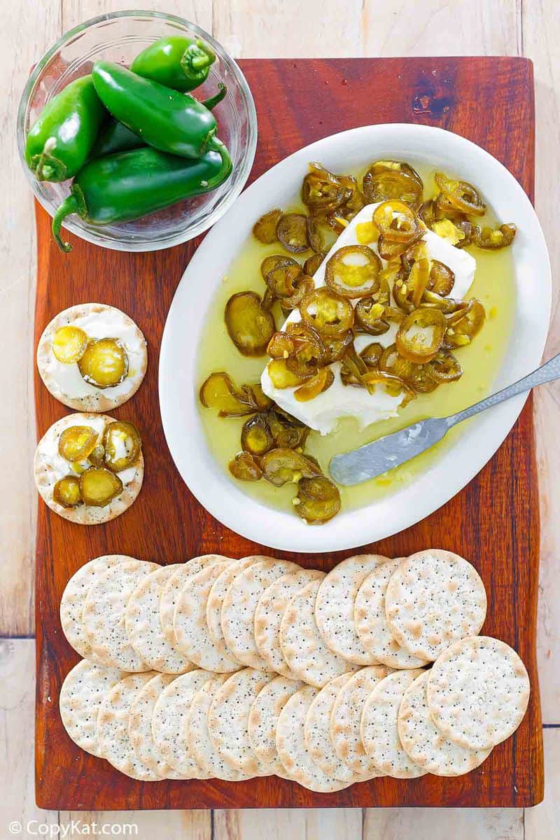 overhead view of candied jalapenos over cream cheese next to crackers