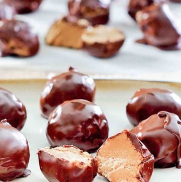 chocolate peanut butter balls on a plate and parchment paper