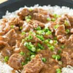 beef tips and gravy on top of rice on a plate