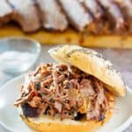 a brisket sandwich with brisked slices in the background