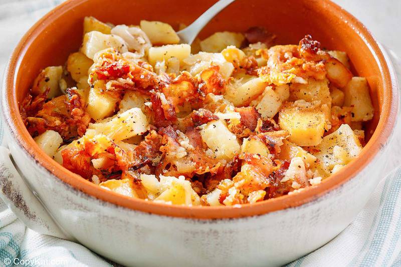 Crockpot cheesy potatoes with onions and bacon in a bowl