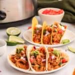 six chicken tacos, lime slices, and diced tomatoes