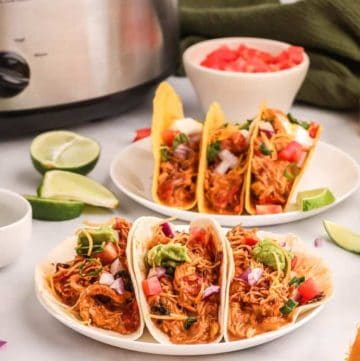 six chicken tacos, lime slices, and diced tomatoes