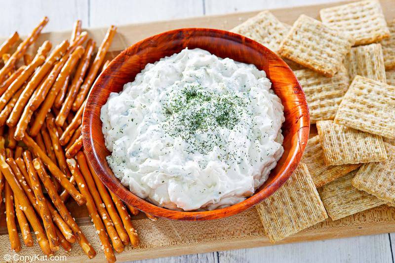 dill pickle dip, pretzel sticks, and crackers on a wood platter