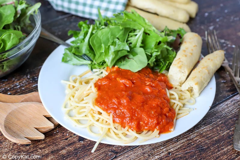 Homemade Olive Garden breadsticks, pasta with marinara, and salad on a plate