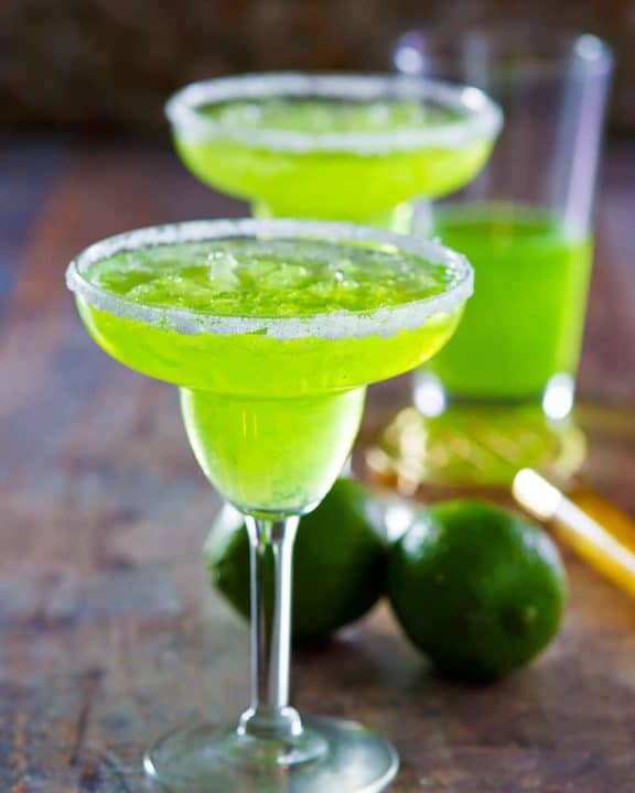 two homemade Red Lobster Dew Garita cocktails and limes