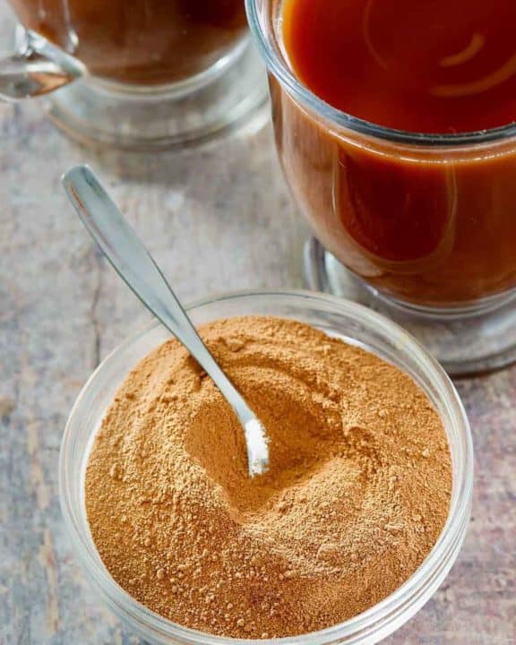 homemade Swiss Miss hot cocoa mix in a bowl next to mugs of hot cocoa