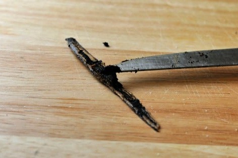 a cut open vanilla bean pod and vanilla seeds on a knife