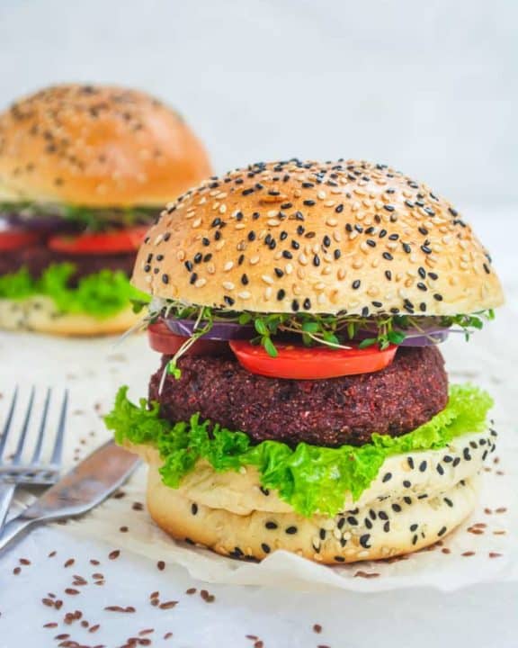 two vegan burgers with lettuce and tomato on sesame seed buns