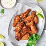 air fryer sweet and spicy chicken wings, lime wedges, and bowls of sauce and dressing