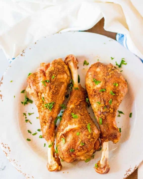 three oven roasted turkey legs on a plate and a kitchen towel