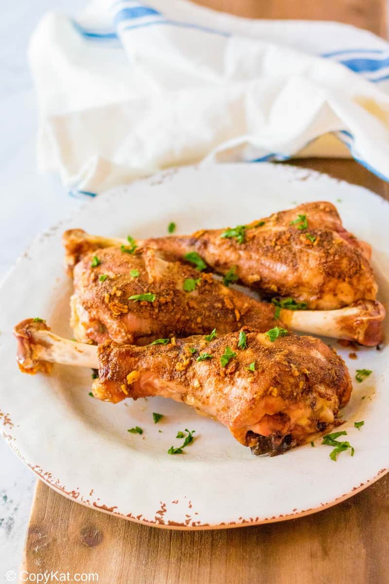 three oven roasted turkey legs on a plate and a kitchen towel
