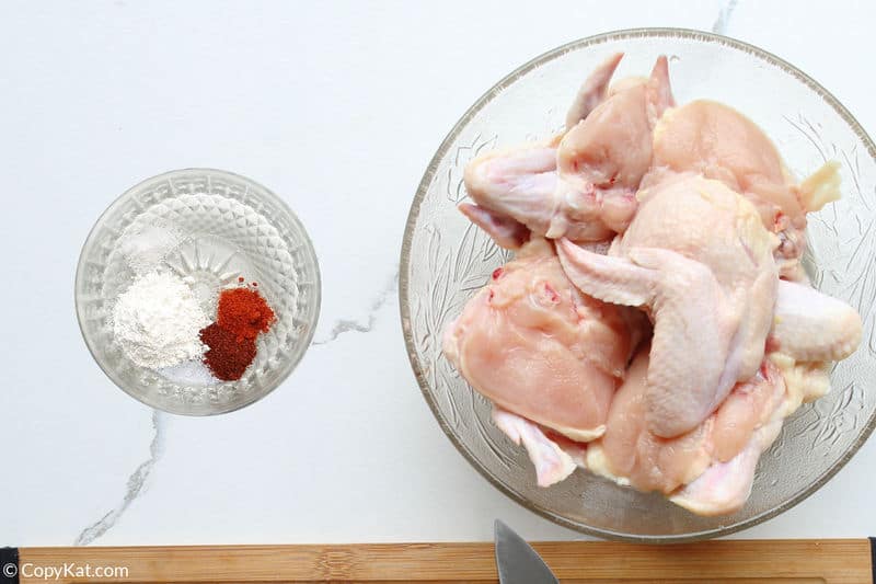 raw chicken wings in a bowl and spices in another bowl