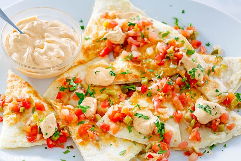 a bowl of homemade Taco Bell quesadilla sauce next to quesadillas on a plate