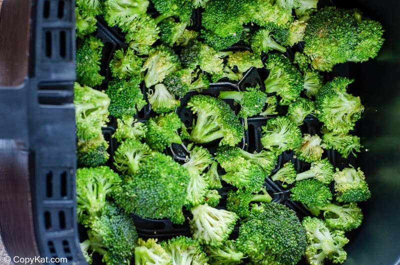 seasoned broccoli in an air fryer basket