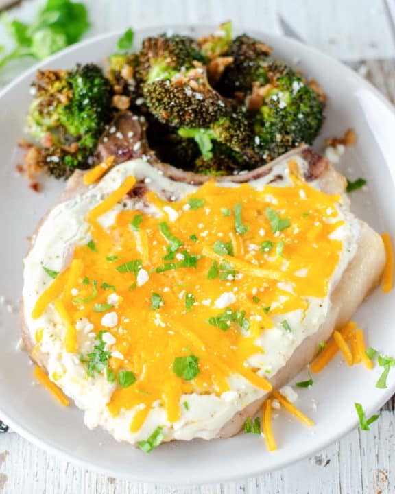 cheesy sour cream baked pork chop and roasted broccoli on a plate