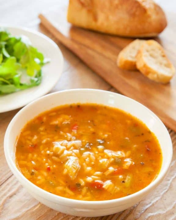 a bowl of chicken gumbo soup and bread on a cutting board