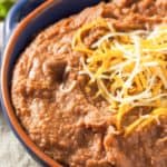 Instant Pot refried beans topped with shredded cheese in a bowl