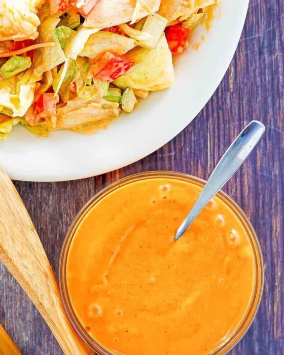 overhead view of homemade French salad dressing in a bowl and on a salad