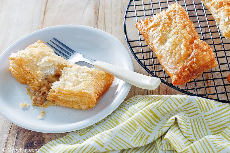 homemade fried apple hand pies on a plate and a rack