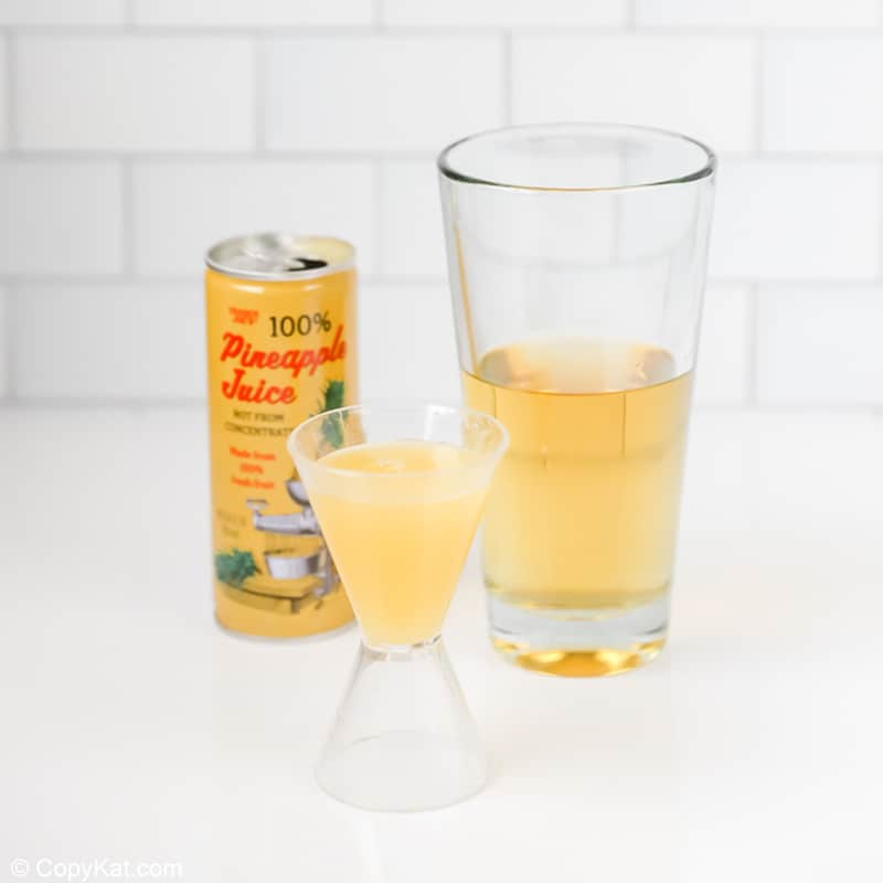 adding pineapple juice to a cocktail shaker with wine