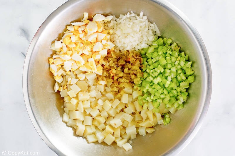 chopped potatoes, eggs, onions, celery, and pickles in a bowl