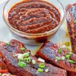a bowl of homemade BBQ sauce and ribs on a plate