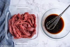 beef strips in a dish and teriyaki marinade in a bowl