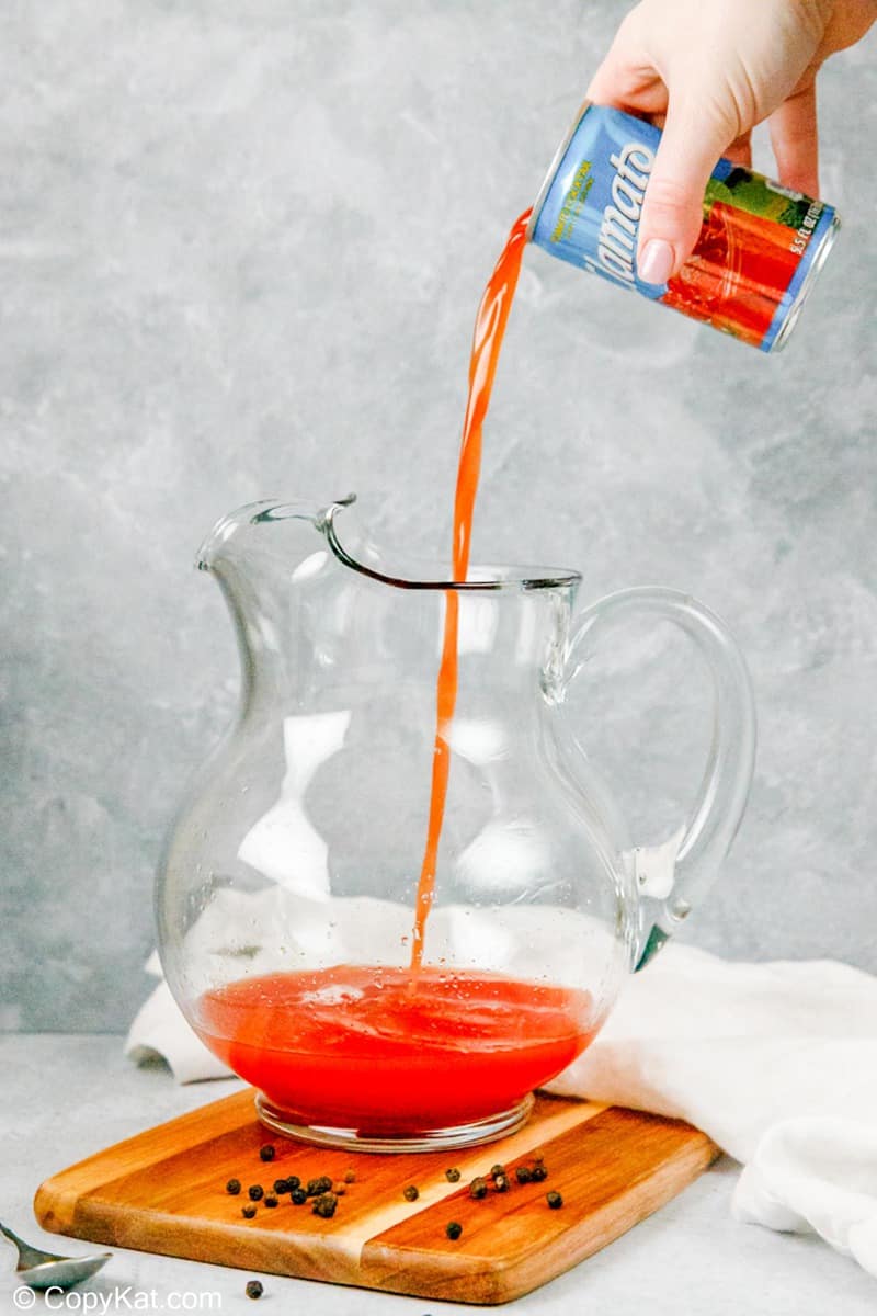 pouring Clamato juice into a pitcher