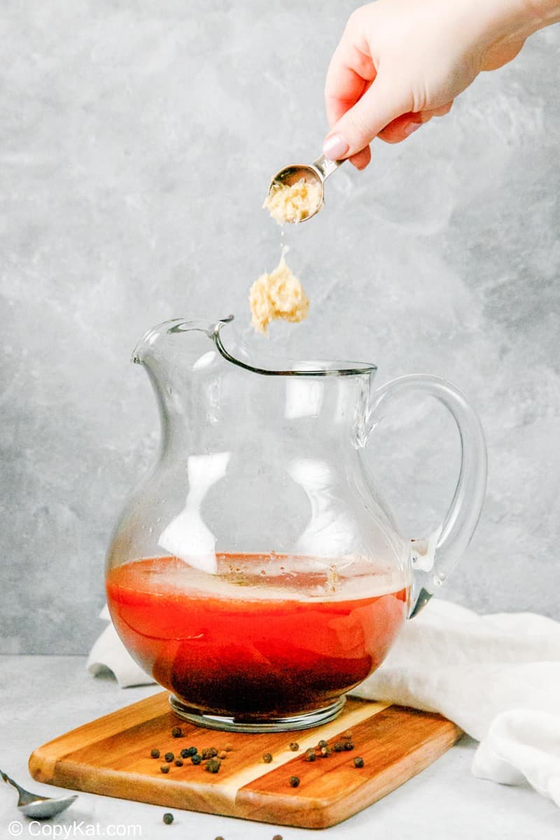putting horseradish into a pitcher of homemade bloody mary mix