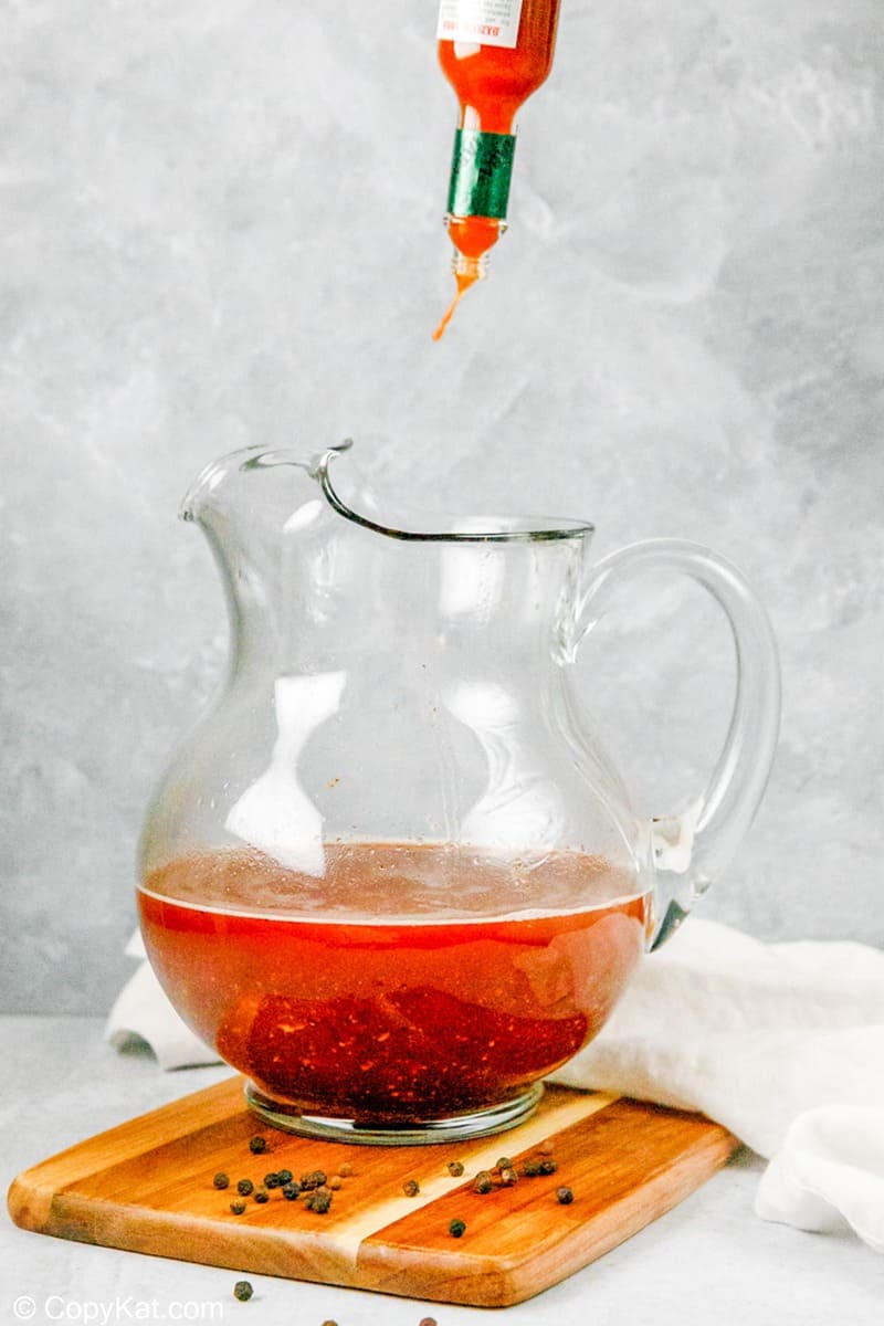 putting hot sauce into a pitcher of homemade bloody mary mix
