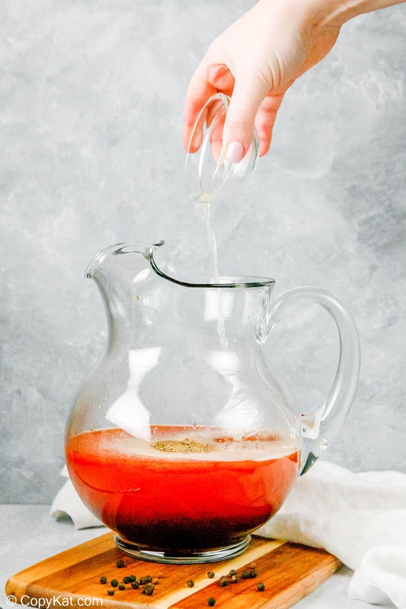 pouring lemon juice into a pitcher of homemade bloody mary mix