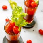 two bloody mary cocktails garnished with celery and tomatos