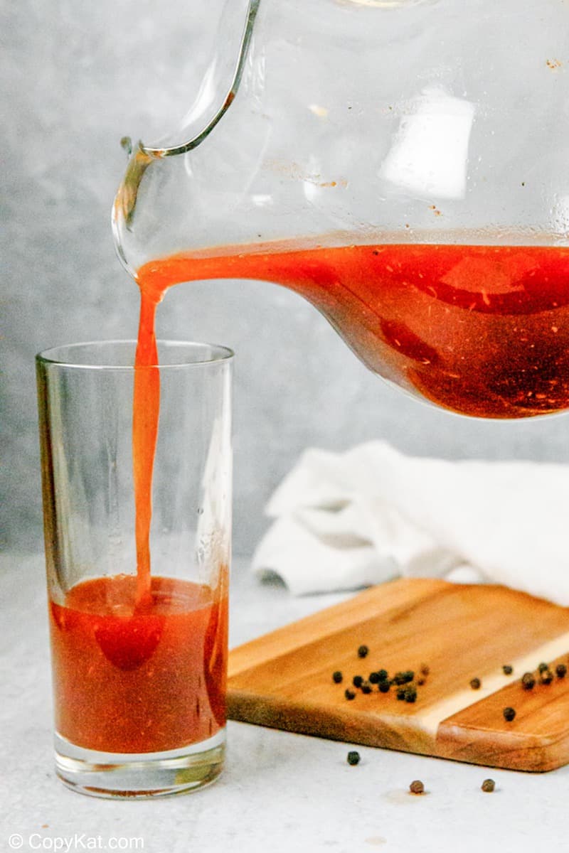 pouring bloody mary from a pitcher into a glass